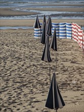 Beach with closed parasols and striped windbreaks by the sea, de haan, Belgium, Europe