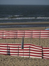 Beach landscape with red and white windbreaks and gentle waves in the background, de haan, Belgium,