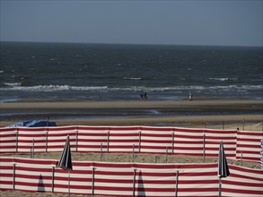 Beach with red and white barriers and a view of the sea and waves on the horizon, de haan, Belgium,