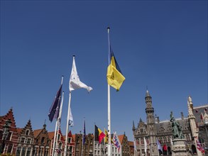 Flags waving against a backdrop of historic buildings on a sunny day, Bruges, Belgium, Europe