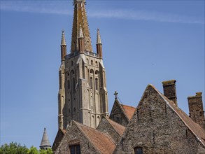 Red church tower and historic buildings under a blue sky, Bruges, Belgium, Europe