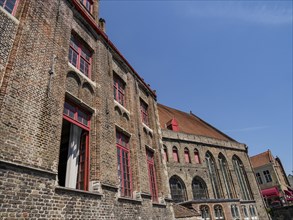 Historic brick architecture with a striking roof and large windows under a sunny sky, Bruges,