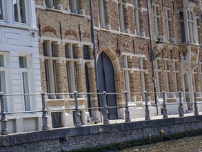 Detailed historic brick faÃ§ade with large windows and a wrought-iron railing on the canal, Bruges,