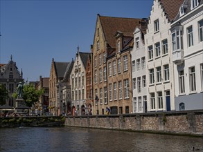 A row of historic buildings along a canal in sunny weather, Bruges, Belgium, Europe