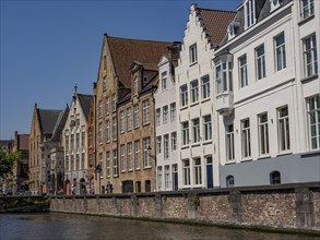 Historic terraced houses along a canal under a clear sky, Bruges, Belgium, Europe