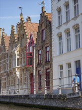 Historic brick houses along a canal under a blue sky, Bruges, Belgium, Europe