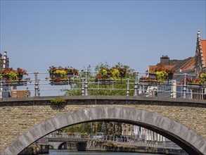 A bridge decorated with flowers over a waterway, surrounded by historic buildings on a clear spring