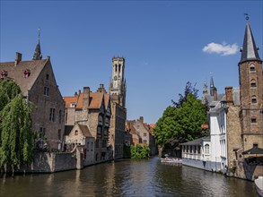 Historic buildings and tower along a quiet canal on a clear day, Bruges, Belgium, Europe