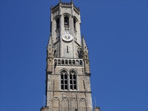 Gothic bell tower with clock in front of a slow sky, Bruges, Belgium, Europe