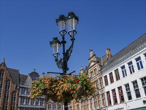 Vintage street lamp with flower decorated traffic light in front of historic buildings under a