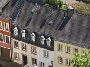 House roofs in an urban area with skylights and satellite dishes, facades in different colours,