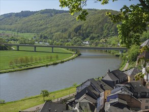 Panorama of a river, crossing bridge, green surroundings and houses at the foot of wooded