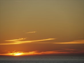 An impressive sunset over the sea with orange-coloured sky and water, langeoog, germany