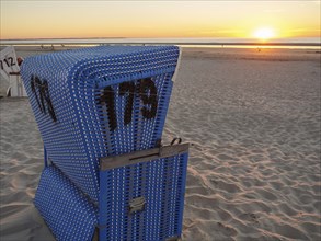 Single blue beach chair on the beach at sunset with a view of the sea, langeoog, germany