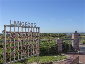 A fence with love locks in front of a vast natural backdrop under a blue sky on Langeoog, langeoog,