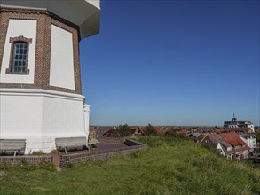 Lighthouse area with surrounding town buildings under a clear blue sky, langeoog, germany