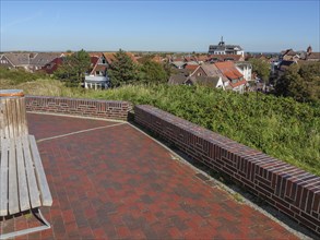 Viewpoint over a town with brick floor and bench under a clear sky, langeoog, germany