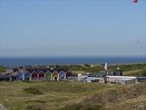 Colourful houses on a dune with a view of the sea under a clear blue sky, langeoog, germany