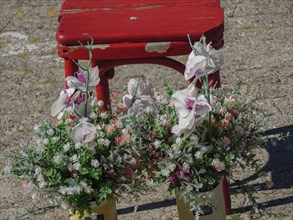 A flower arrangement with orchids in front of a rustic red bench on sandy ground, langeoog, germany