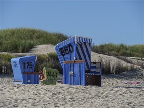 Blue beach chairs on a sandy beach, with sand dunes and beach grass in the background, langeoog,