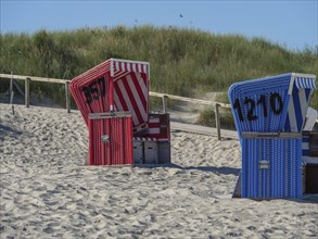 Two beach chairs with the background of grassy dunes on the beach, langeoog, germany