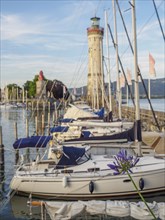 A busy marina with several sailing boats and a lighthouse in the background, Meersburg, Lake