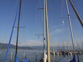 View of moored sailing boats with high masts in the harbour under a cloudless sky, Lindau, Lake