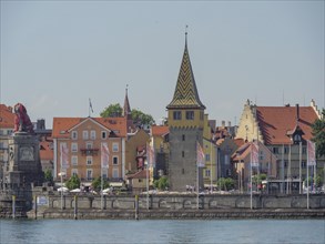 Historic buildings and a city tower with flags at the harbour, Lindau, Lake Constance, Germany,