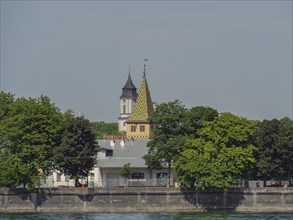 Colourful church with trees directly on the lake on a clear day, Lindau, Lake Constance, Germany,