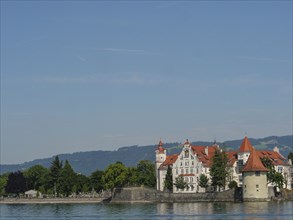 Urban scene with historic buildings and towers along the lakeshore under a clear summer sky,