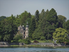 Elegant castle with characteristic towers and facades, surrounded by dense forest and water on the