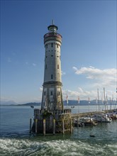 High lighthouse on the water with boats and clear sky in the background, Lindau, Bavaria, Germany,