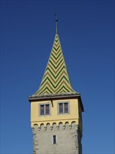 A medieval tower with a colourful tiled roof, in front of a clear sky, Lindau, Bavaria, Germany,