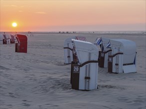 Several beach chairs stand on the quiet beach during sunset, dusk bathes the scene in soft light,