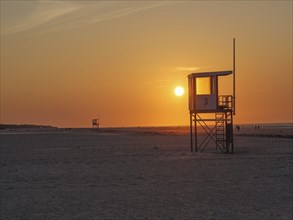 A watchtower stands on the beach at sunset, orange sky in the background, juist, east frisia,