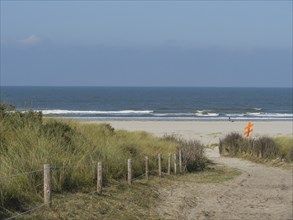 Sandy path leads to the beach, dunes with green plants, quiet atmosphere, juist, east frisia,