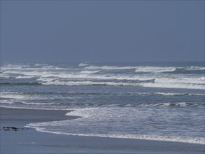 Swell at the sea under blue sky, shallow water at the beach, juist, east frisia, germany