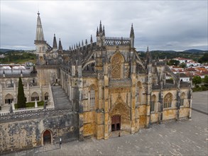 Impressive Gothic cathedral with a grand entrance and detailed towers under a cloudy sky, aerial