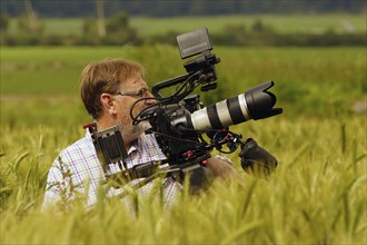 Cameraman at work in a wheat field