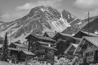 Nested old wooden houses, in the background the summit of the mountain Scex de Marenda, historic