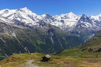 Alpine meadows and mountain hut at the summit of Corne de Sorebois, with the snow-covered peaks of