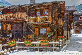 Paved footpath surrounded by old wooden houses, flower boxes on balconies and windows, historic