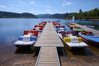 A picturesque scene with colourful pedal boats and wooden boats on a jetty in front of the