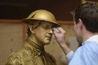 A make-up artist applies gold paint to an actor's face before a performance