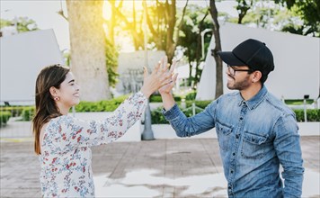 Girl and a guy shaking hands on the street. Two young smiling friends greeting in the street.