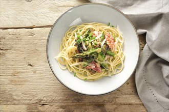 Vegetable sauce of green asparagus and tomatoes with parmesan and parsley garnish on spaghetti in a