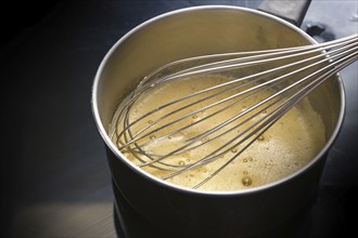 Preparation of hollandaise sauce, egg mixture is whisked at low temperature until foamy in a steel