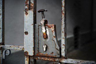 Nostalgic rusty door lock with a modern lock cylinder on a metal entrance grille, copy space in the