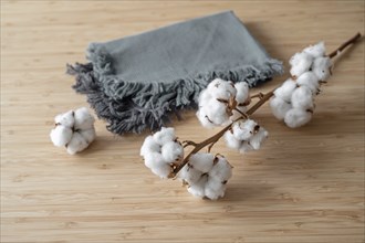 Fabrics made from sustainably and fairly grown cotton, two cloths and a twig on a wooden table,