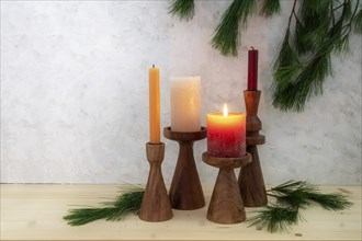 Four candles on wooden stands, one is lit for the first Advent, pine branch decoration, light